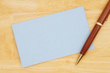 Blank blue paper index card with pen on wood desk
