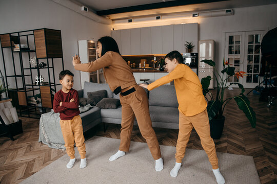 Mom Teaches Her Two Sons To Do Sports Physical Exercises In The Morning At Home