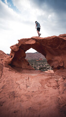 A guy standing on a arches in the valley of fire state park, USA