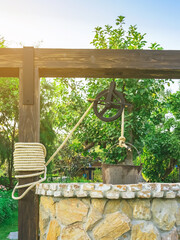 Beautiful artesian well made by stones and wheel pulley with metal bucket and rope in peaceful...