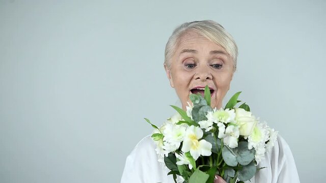 Happy senior woman holding bouquet of beautiful flowers