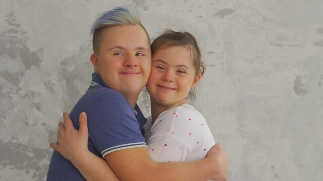 Cheerful teenage couple with Down Syndrome hugging