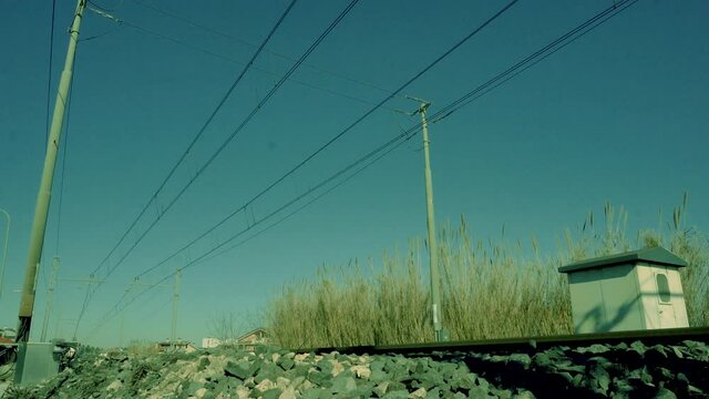 In summer railway train passes fast from left to right down perspective under blue sky (coming)