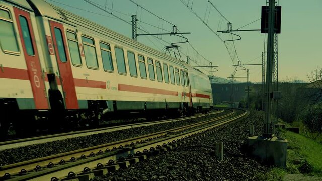In summer railway train passes fast from left to right down perspective under blue sky (going)