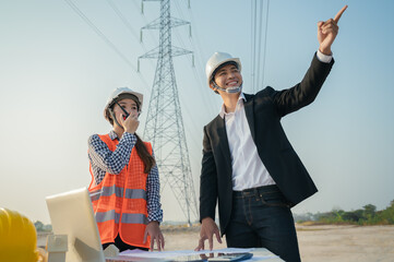 engineer worker with electric pole and model windmill in morning blue sky
