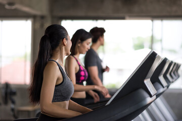 Fototapeta na wymiar woman run and talk with friends on treadmills in gym