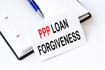 PPP LOAN FORGIVENESS text, pen are on thedesktop. Business concept.