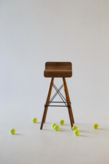 Tall vintage wooden chair and tennis balls lying around on a light gray background.