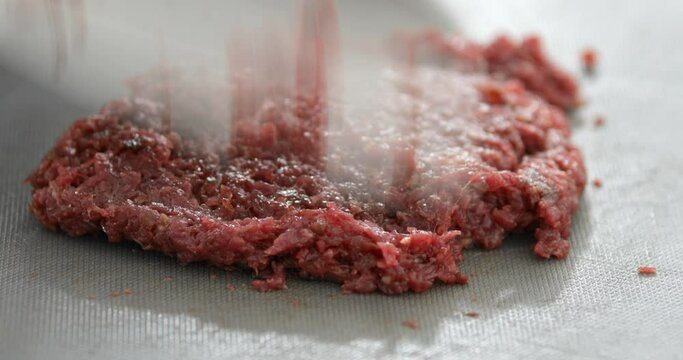 Horse meat finely chopped using sharp knife, preparing Steak Tartare, or minced steak, close-up