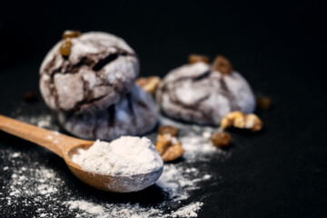 Chocolate cookie with nuts and flour. Chocolate crinkle cookies on dark black background. Christmas, recipe concept.  Chocolate cookies in powdered sugar on black background.