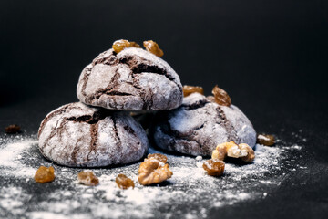 Chocolate Crinkle Cookies close-up on a black background. Chocolate cookie with nuts, raisins and flour. Selective focus