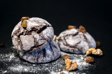 Chocolate Crinkle Cookies close-up on a black background. Chocolate cookie with nuts, raisins and flour. Selective focus