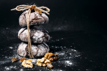 Chocolate cookie with nuts and flour. Chocolate chip cookie on black background with copy space for text, closeup.