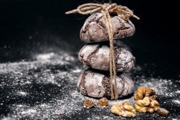 Chocolate cookie with nuts, raisins and flour. Chocolate crinkle cookies on dark black background. recipe concept.  Chocolate cookies in powdered sugar on black background.