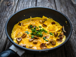 Breakfast - scrambled eggs with champignon and chive in frying pan
