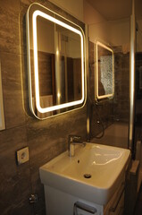 
Detail view of a bathroom, with a view of the vanity with an illuminated mirror. Detailansicht eines Badezimmers, mit Blick auf den Waschtisch mit einem beleuchtetem Spiegel