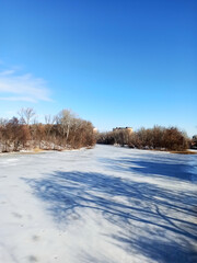 Winter landscape, white ice on a frozen river with blue sky