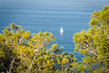 Sailboat sailing in the calm turquoise waters of the Mediterranean Sea in Cap Negre on a summer day with blue sky, Javea, Alicante, Spain