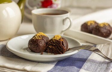 Hot tea in a white cup and homemade chocolate cake on the table.