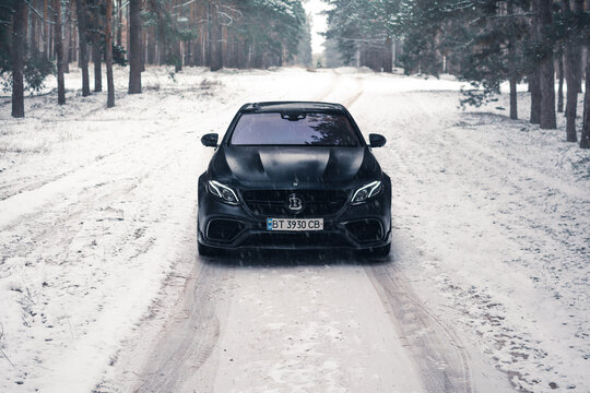 Kherson, Ukraine - February 2021. Powerful Mercedes-AMG E63S Brabus 800 in a matte black color on the snowy road in the winter forest.