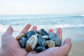 Stones in male's hands near the ocean