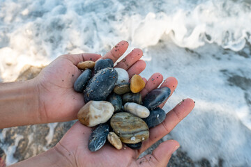 Stones in male's hands near the ocean