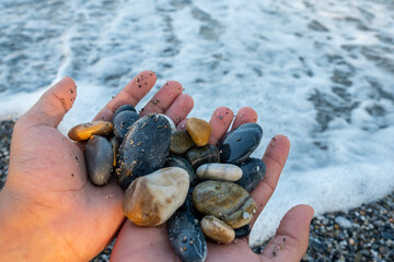 Stones in male's hands near the ocean