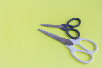 Scissors on a yellow background.White large and black small scissors for work and creativity.