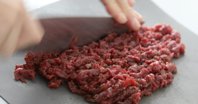 Horse meat finely chopped using sharp knife, preparing Steak Tartare, or minced steak, close-up