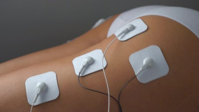 Myostimulation of the girl's buttocks and legs with vibration impulses from the electrodes. Slimming, treatment and rehabilitation in a beauty salon