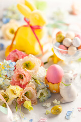Happy Easter background with colorful eggs, candy and bunch of flowers. Table decorating for holiday.