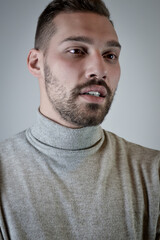 Fototapeta premium Portrait of a young brown-haired man with a short beard and a gray turtleneck sweater 