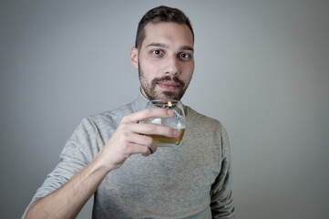 Portrait of a young man with a short beard who drinks a glass of beer