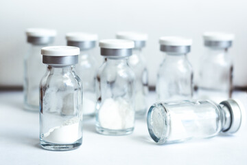 Glass sealed vials with medicine in powder form on light background, selective focus