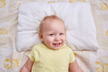 A smiling baby lies on a white pillow. pillowcase mockup