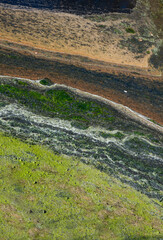 Eutrophication, dense covering of rotting algae in several colors on the water in a ditch