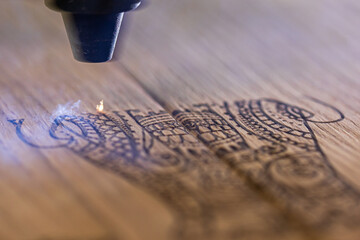 laser engraves the image of an Indian elephant on a wooden surface