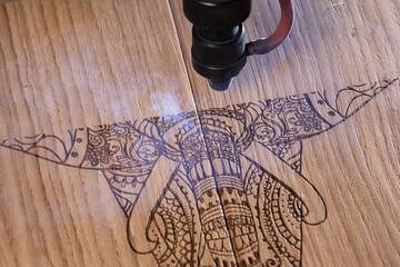 laser engraves the image of an Indian elephant on a wooden surface - 417177411