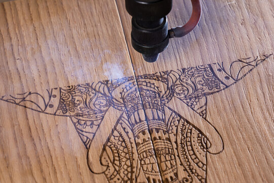 laser engraves the image of an Indian elephant on a wooden surface