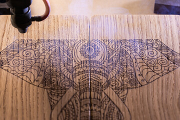 laser engraves the image of an Indian elephant on a wooden surface - 417177668