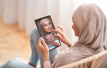 Woman making video call with muslim friend using smartphone
