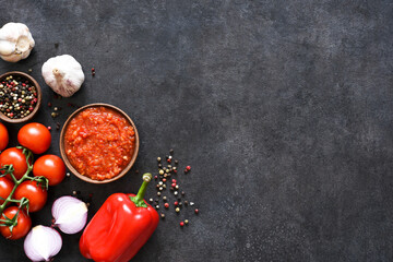 Tomato sauce with pepper and garlic on a dark concrete background.