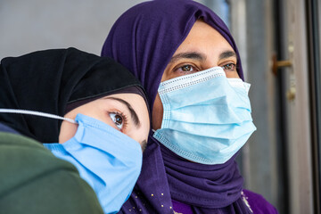 Arabic woman looking from the window during quarantine time and wearing mask