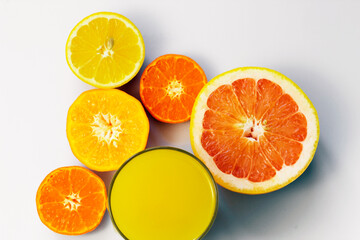 Fototapeta na wymiar Sliced citrus on a white background with a glass of fresh juice. Grapefruit, lemon, tangerine