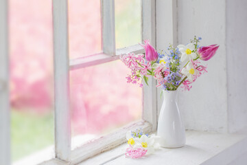 spring flowers in white vase on old windowsill