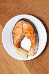 Cooked appetizing salmon steak on a snow-white plate.