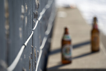 Gabion fence made of steel bars filled with gray granite stones. Park bench with beer bottles. Side view. Selective focus. Winter in Germany.