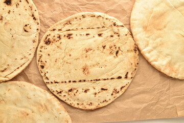 Several freshly baked pita bread on brown paper, close-up, top view.