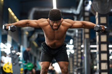 Strong black guy bodybuilder making workout with dumbbells