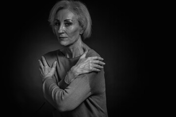 Classic black-and-white dramatic portrait of an elderly blonde woman in Studio on black background